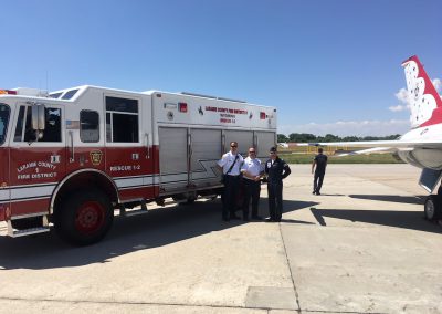 Laramie County Fire District #1 Rescue 1-2 truck with personnel on an airfield beside an aircraft demonstrates FEPP equipment in service