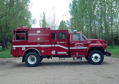Red Laramie County Fire District #1 Brush 1-1 wildland brush truck parked near trees is an example of FEPP equipment in service